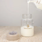 Moedermelk wordt ingeschonken in glazen bewaarflesje van Mom Glowth met maatstreepjes – lekvrije schroefdop, borosilicaatglas, BPA-vrij